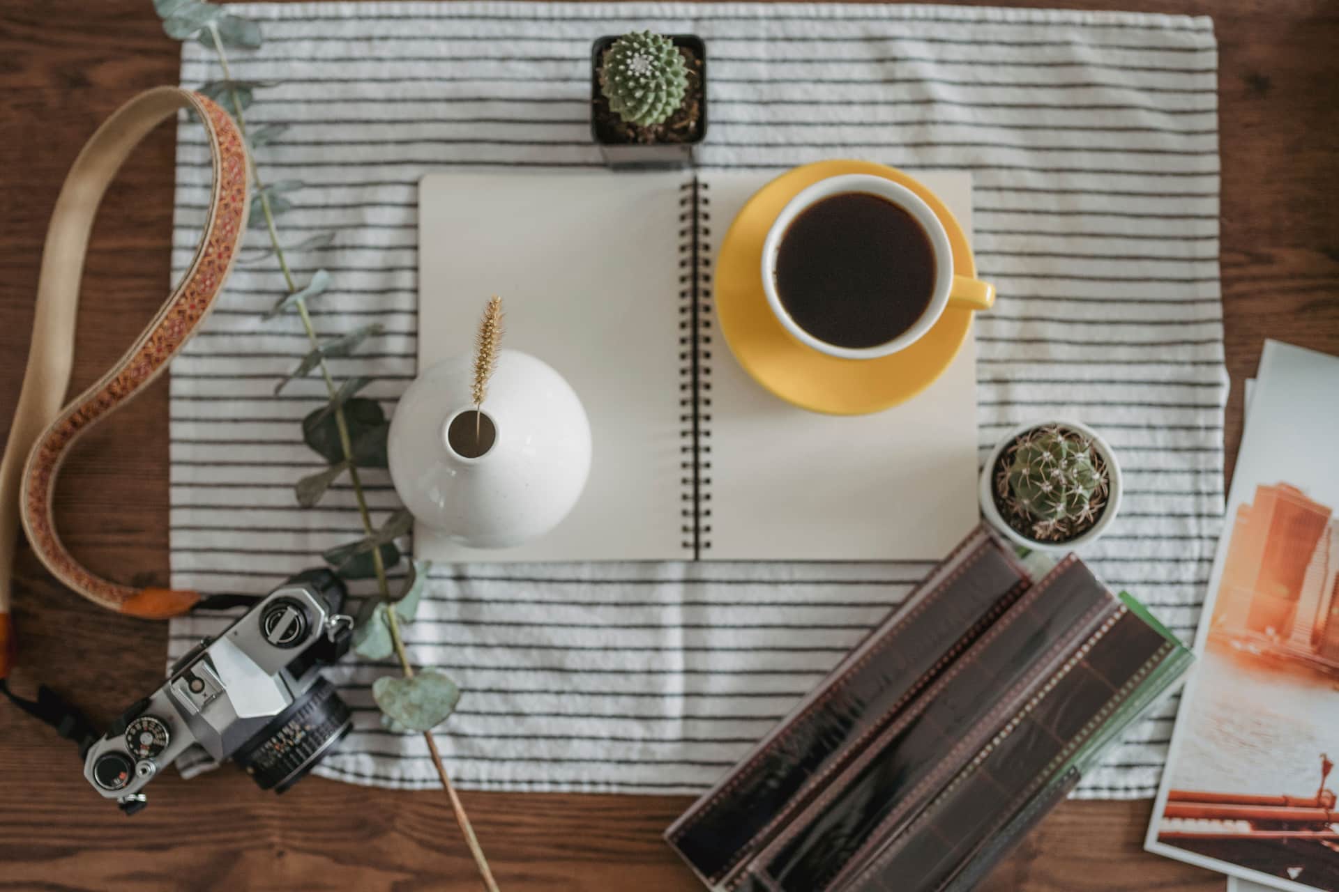 A camera resting on a table beside a notebook